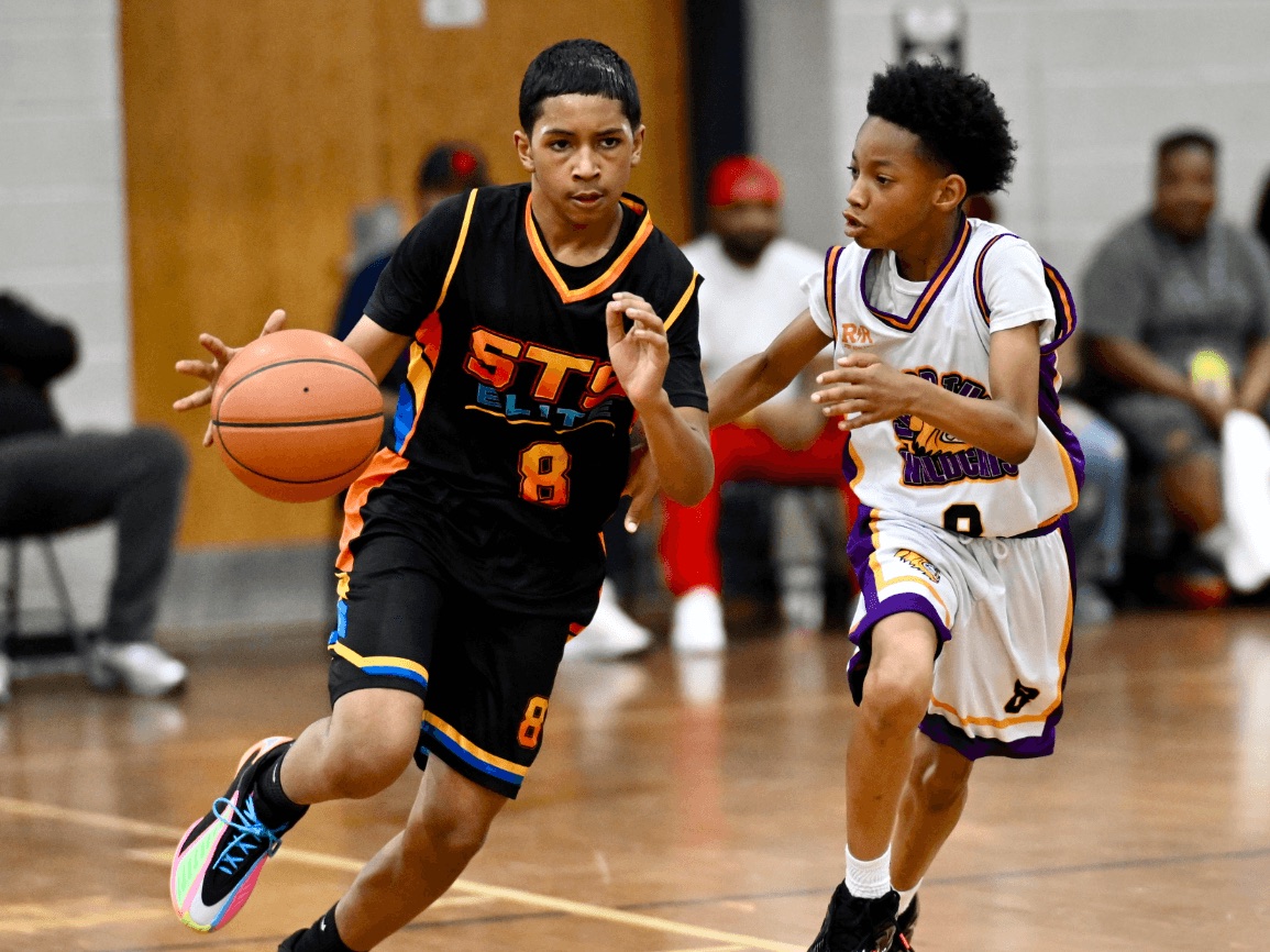 A young IMPACT Sports player driving the ball up the court past a defender.